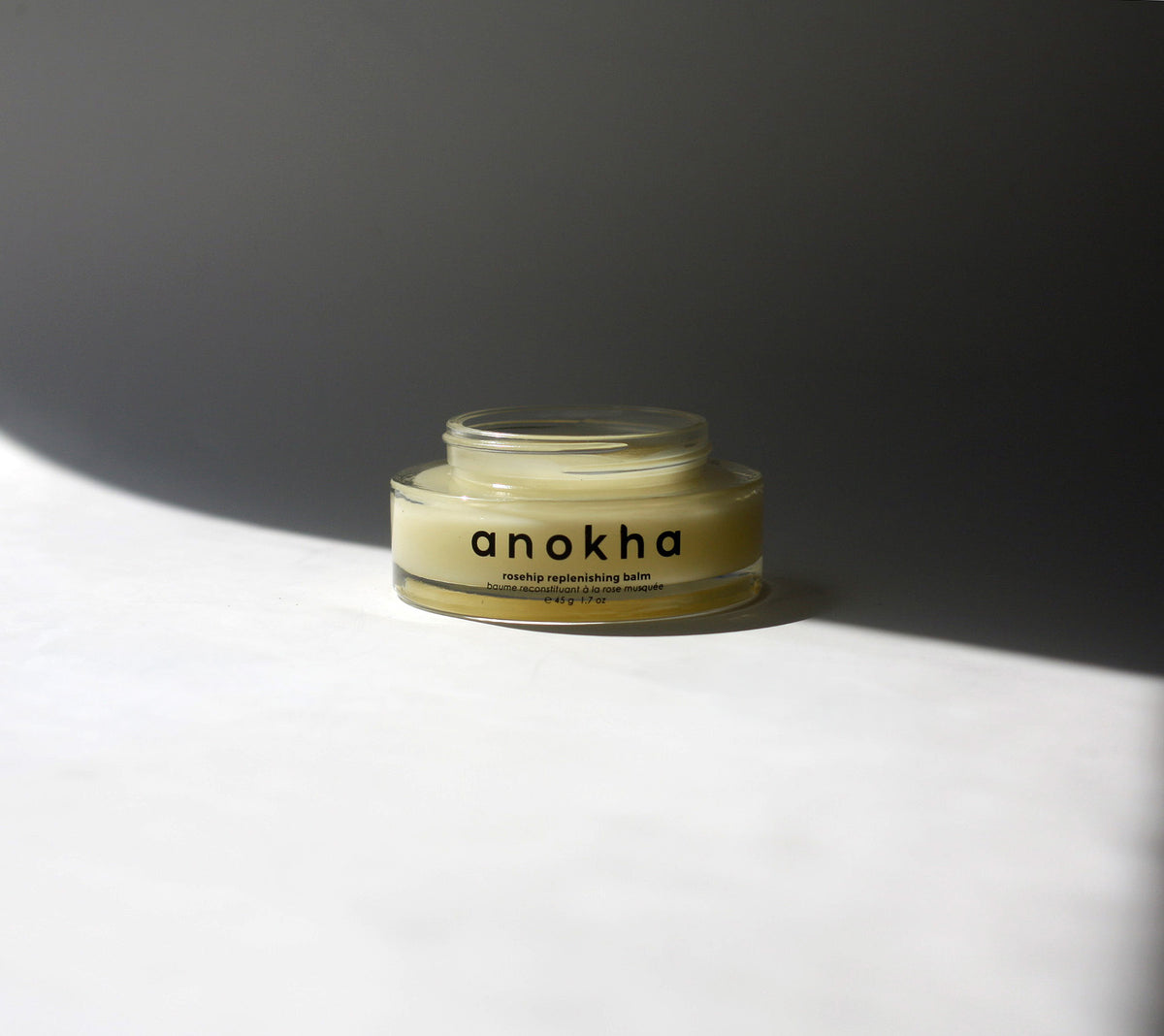 anokha rosehip replenishing balm clear jar yellow balm shadowed background