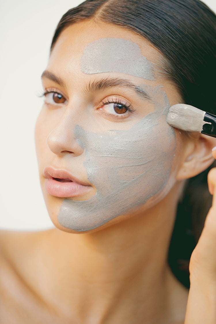 woman applying anokha skincare blue clay clarifying masque to face