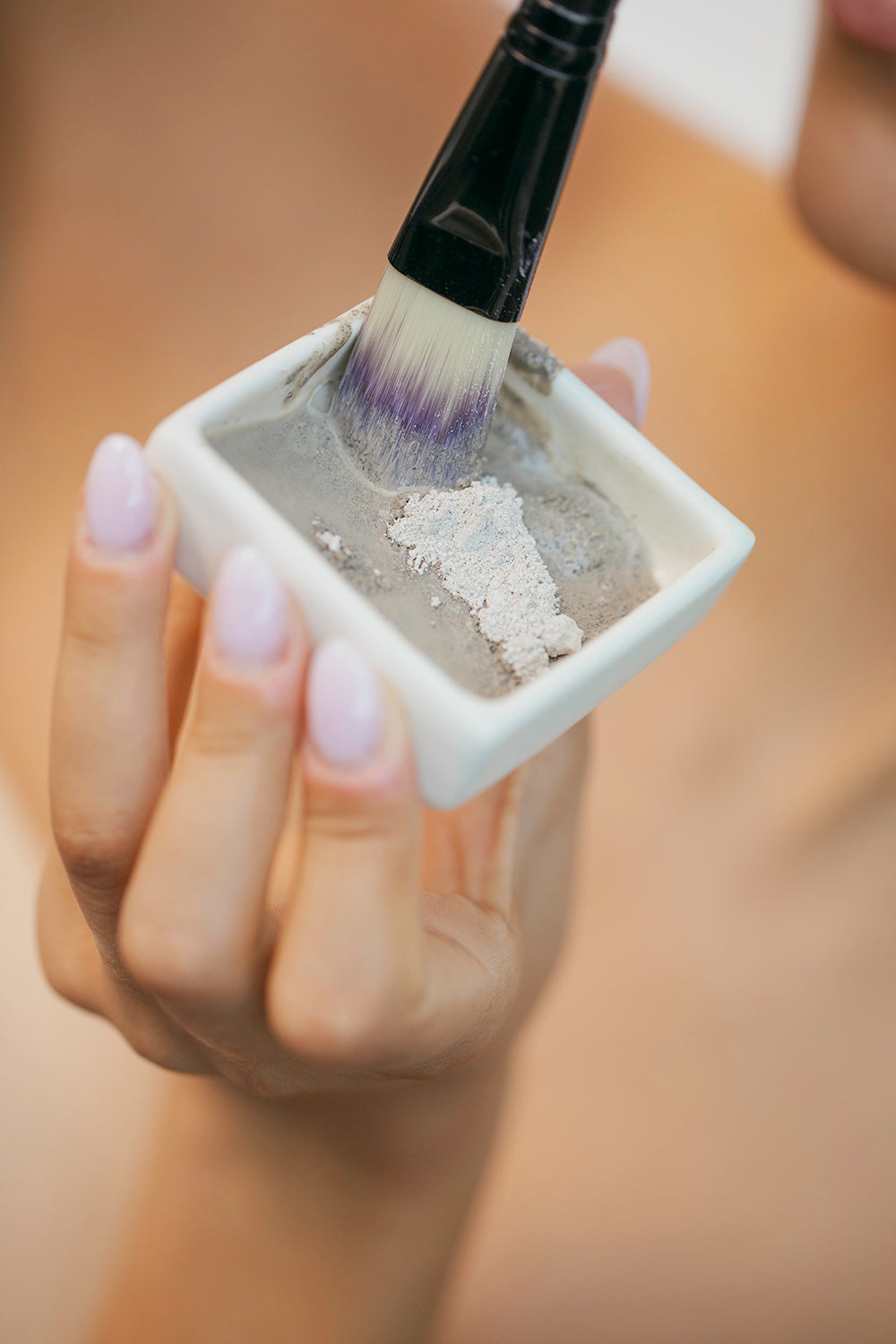 woman's hand hlding porcelain dish with brush and dry clay powder 